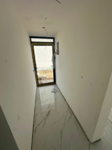 Investment opportunity in Ulcinj: unfinished hallway with white walls, glossy tiles, and doorway—listed by montenegro-listings.me.