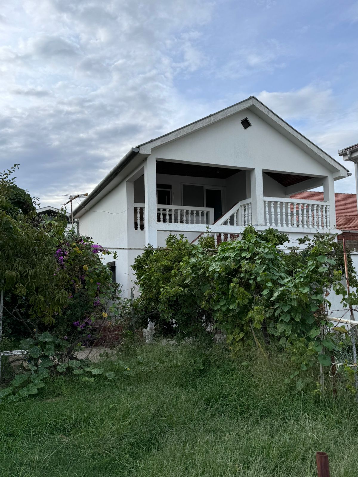 Modern white house with porch, lush garden, and balcony—prime Ulcinj real estate. Invest with montenegro-listings.me by ekosphere doo.