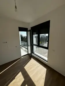 Bright, modern room in Ulcinj with wood floors and balcony access—invest in Montenegro real estate via montenegro-listings.me by ekosphere doo.