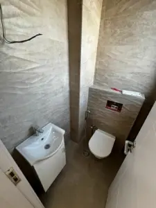 Stylish modern bathroom in Ulcinj, Montenegro—beige tiles, wall toilet, sink cabinet; ideal investment via montenegro-listings.me (EkoSphere).
