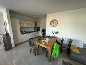 Modern Ulcinj kitchen with spacious dining area, white cabinets, and wood table—exclusive real estate on montenegro-listings.me by ekosphere doo.