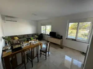Modern, sunlit Ulcinj living room with corner sofa, dining for 4, large windows—prime Montenegro property from Ekospheres montenegro-listings.me.