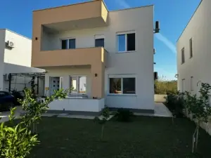 Modern 2-story house in Ulcinj, Montenegro: beige & white facade, balcony, lush lawn—exclusive on montenegro-listings.me by ekosphere doo.