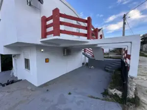 Modern white two-story property in Ulcinj, Montenegro, with red railings, exterior stairs & parking—ideal investment via montenegro-listings.me by ekosphere doo.