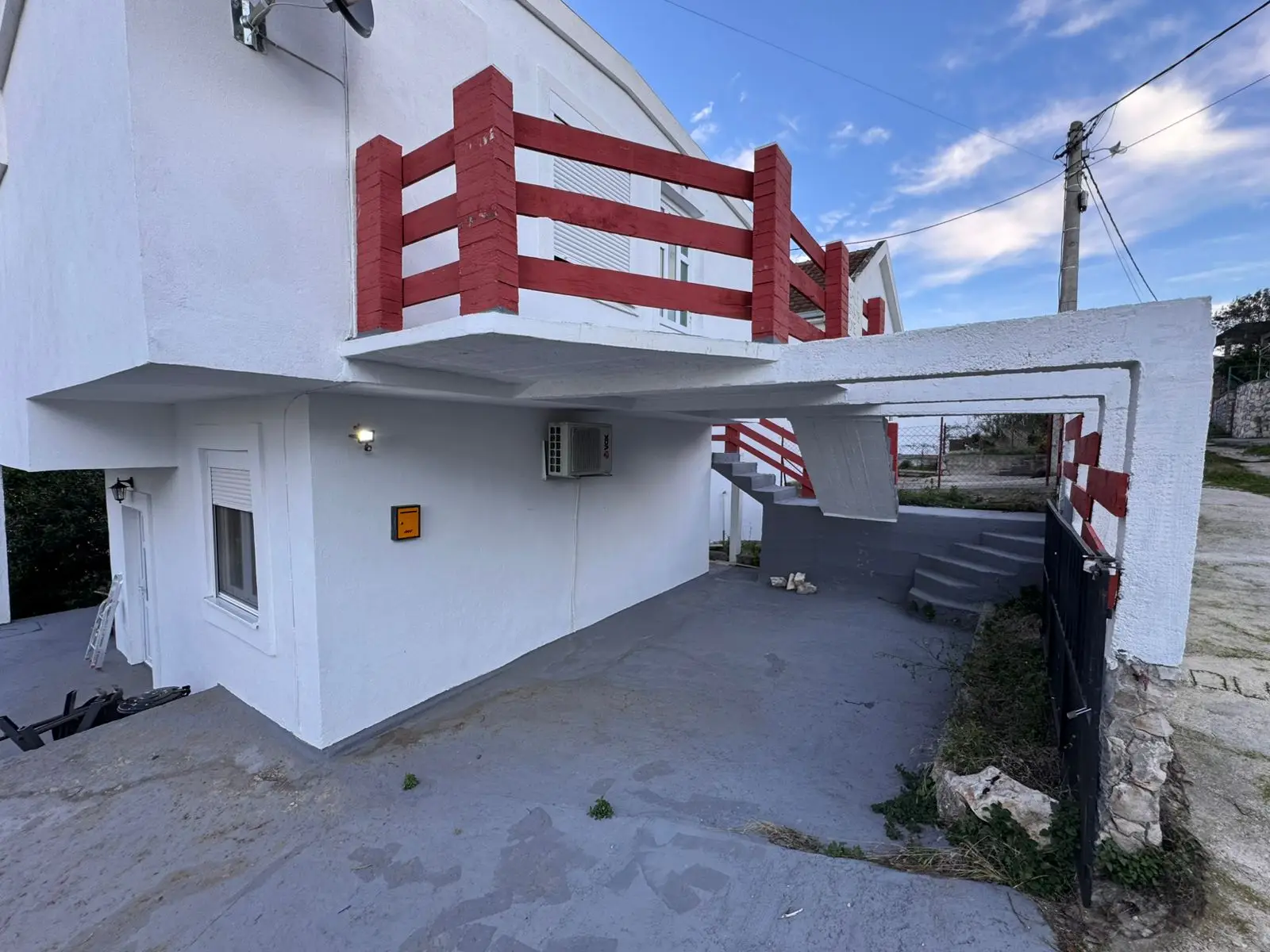 Modern white two-story property in Ulcinj, Montenegro, with red railings, exterior stairs & parking&mdash;ideal investment via montenegro-listings.me by ekosphere doo.