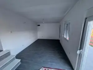 Modern investment opportunity in Ulcinj: bright room with white walls, dark floors, stairs, 3 windows, and glass door by ekosphere.