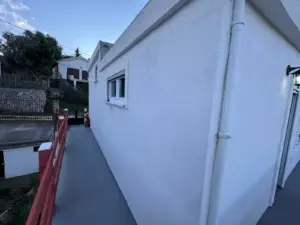 Modern white building with window, red railing, and walkway in Ulcinj, Montenegro—prime real estate by Ekosphere & montenegro-listings.me.