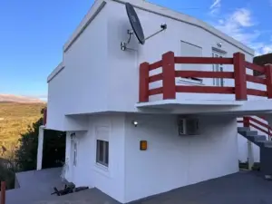 Stunning two-story white home in Ulcinj, Montenegro with red balconies—prime real estate investment via montenegro-listings.me by ekosphere doo.
