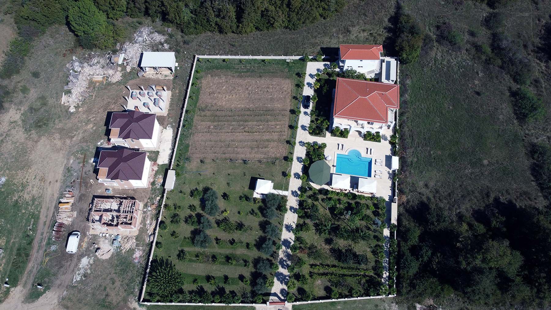 Prime Ulcinj real estate: garden, pool, red-roofed villa, Ekosphere homes under construction amid lush greenery. montenegro-listings.me.