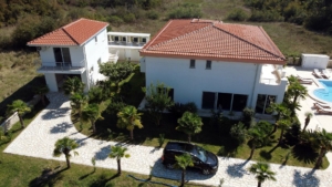 Exclusive aerial view of a luxury white villa with pool, palm trees, and lush Ekosphere landscaping in Ulcinj—listed on montenegro-listings.me.
