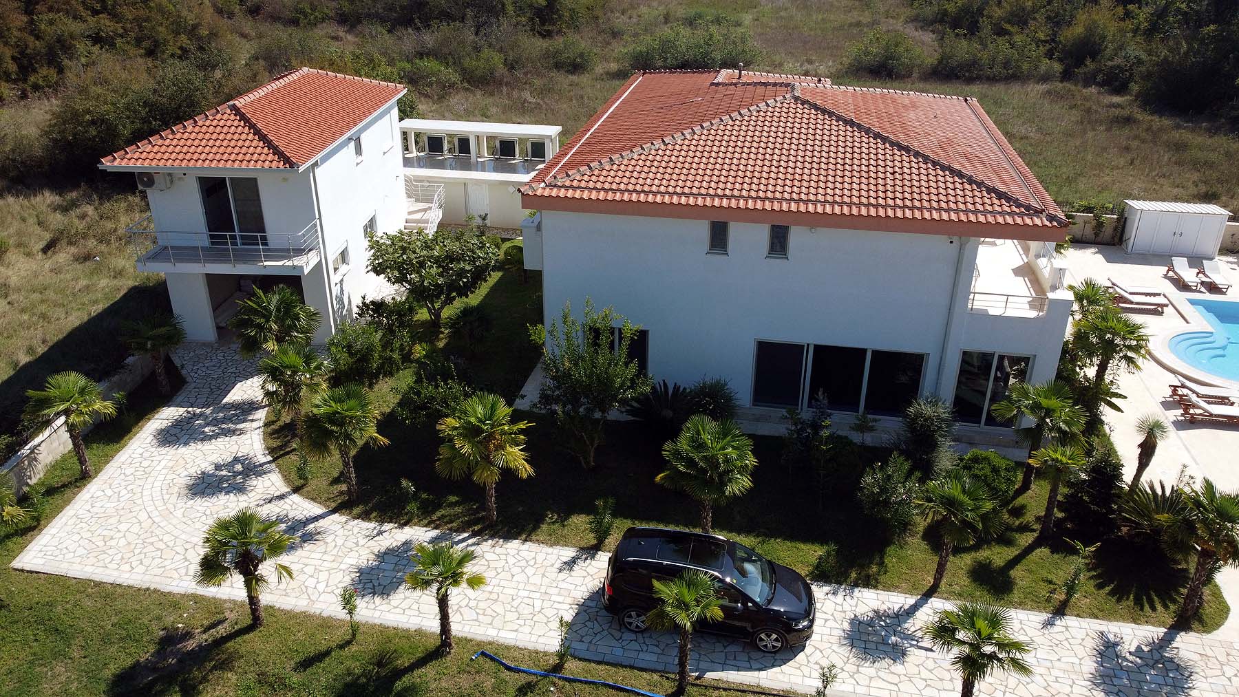 Exclusive aerial view of a luxury white villa with pool, palm trees, and lush Ekosphere landscaping in Ulcinj&mdash;listed on montenegro-listings.me.