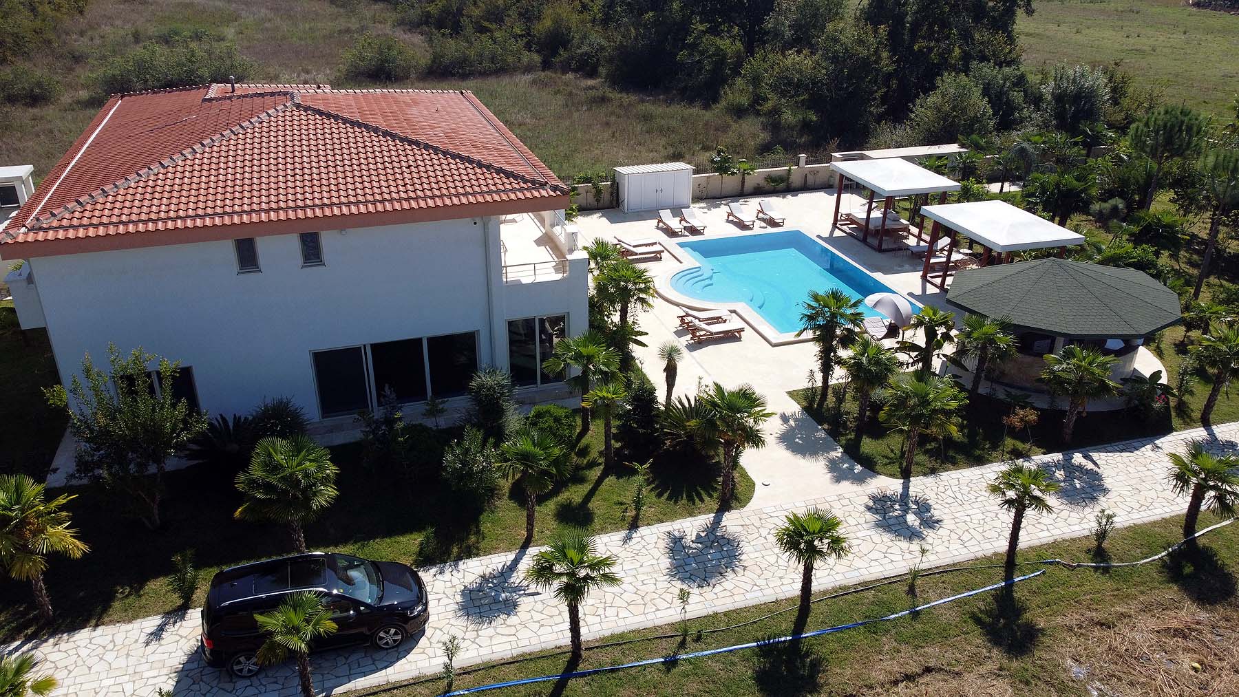 Aerial view of luxury Ulcinj villa for sale: red-tiled roof, pool, gazebo, palm-lined drive&mdash;exclusive at montenegro-listings.me by ekosphere doo.