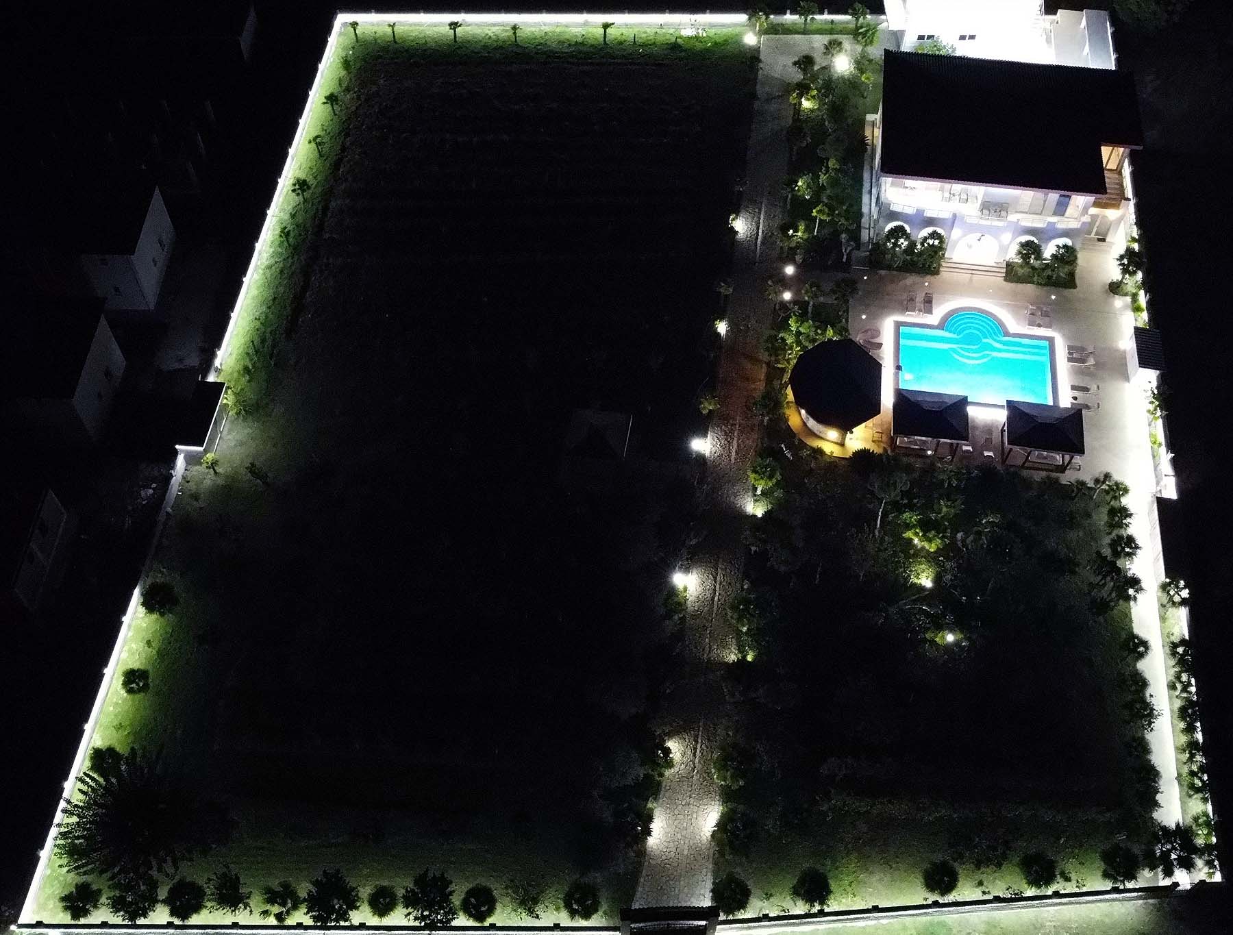 Stunning aerial night view of an illuminated Ulcinj property with pool, gardens&mdash;prime investment via Montenegro-Listings.me by Ekosphere.