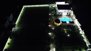 Stunning aerial night view: luxury modern home with pool, lush gardens, and illuminated fencing in Ulcinj Montenegro. An exclusive montenegro-listings.me by ekosphere doo property investment opportunity.
