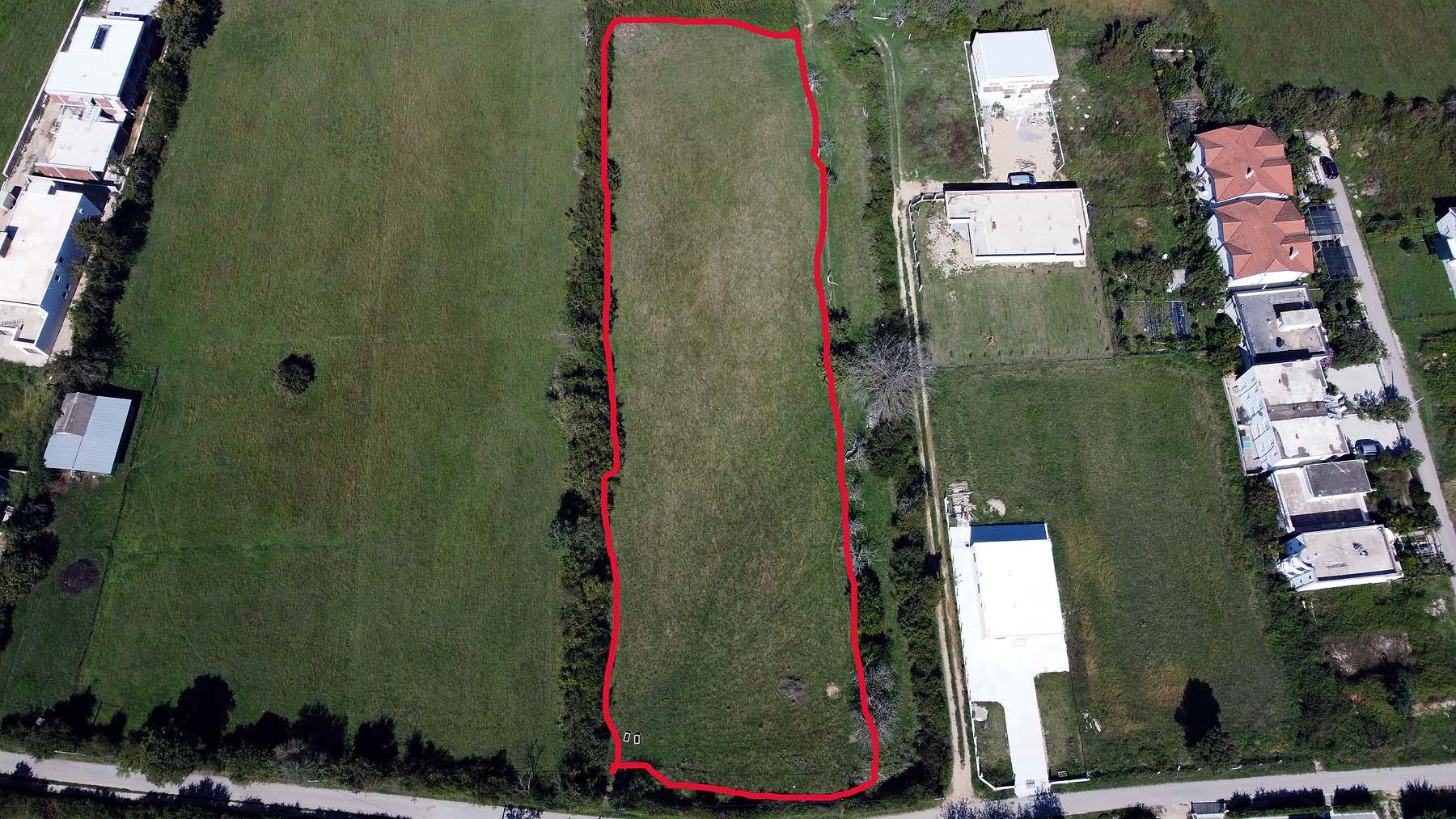 Prime rectangular land plot in Ulcinj, Montenegro—outlined in red, near homes & roads. Ideal investment via montenegro-listings.me by Ekosphere.