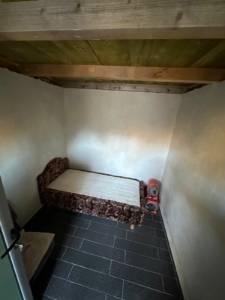 Charming Ulcinj property: sleek black-tiled floor, wooden ceiling, cozy bed—great Montenegro investment via montenegro-listings.me.