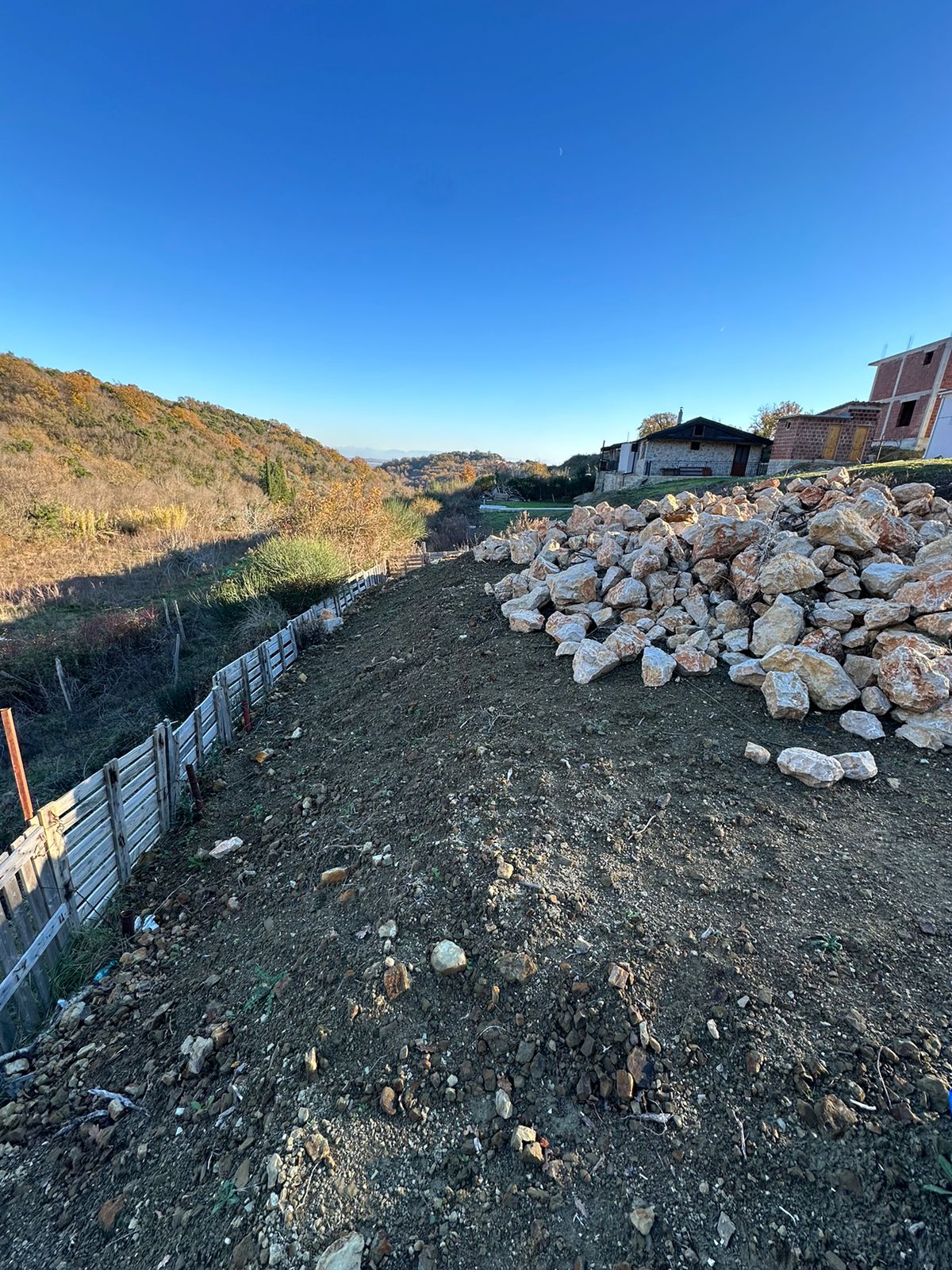 Prime Ulcinj land with development potential&mdash;clear lot, rock pile, fenced, scenic hills/homes. Montenegro-listings.me by ekosphere doo.