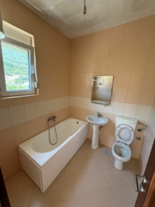 Charming Ulcinj bathroom with tan tiles, bright window, modern fixtures—ideal property investment on montenegro-listings.me by ekosphere doo.