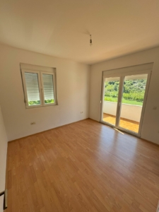 Invest in Ulcinj: bright room with wood floors, white walls, balcony & green views. Listed by montenegro-listings.me (ekosphere doo).