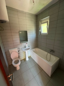 Modern bathroom in Ulcinj: light gray tiles, quality fixtures, bathtub & window—prime investment with montenegro-listings.me by ekosphere doo.