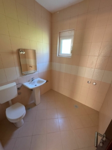 Modern bathroom in Ulcinj with beige tiles, window, quality fittings—prime Montenegro real estate by montenegro-listings.me (Ekosphere DOO).