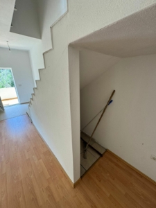 Modern staircase with storage, light wood floors, and pristine white interiors—prime Ulcinj property at montenegro-listings.me by Ekosphere.