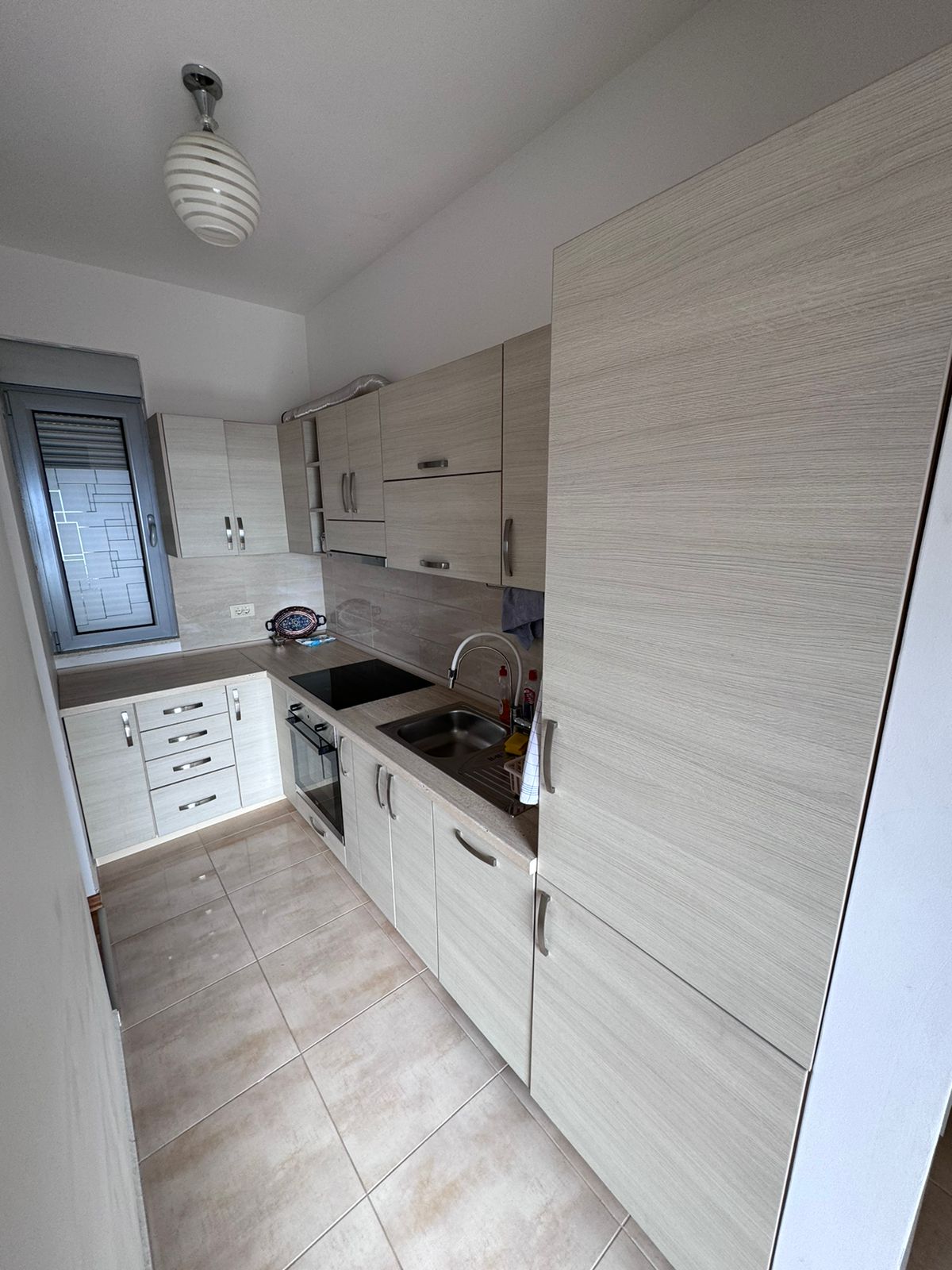 Modern narrow kitchen in Ulcinj with light wood cabinets, built-in oven, tiled floor&mdash;ideal investment on montenegro-listings.me by ekosphere doo.