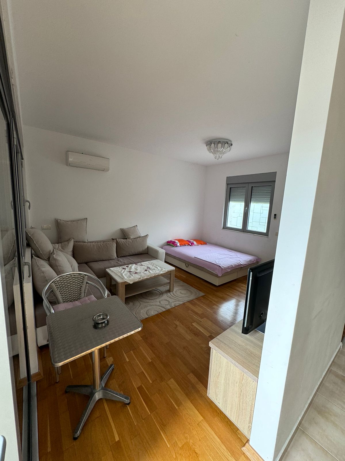Modern, sunlit Ulcinj apartment with wood floors, cozy L-sofa, dining area, double bed by window&mdash;exclusive on Montenegro-Listings.me by Ekosphere doo.