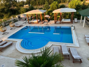 Luxurious pool oasis with blue tiles, lounge chairs, cabanas & chic seating—prime Ulcinj investment. Listed on montenegro-listings.me.