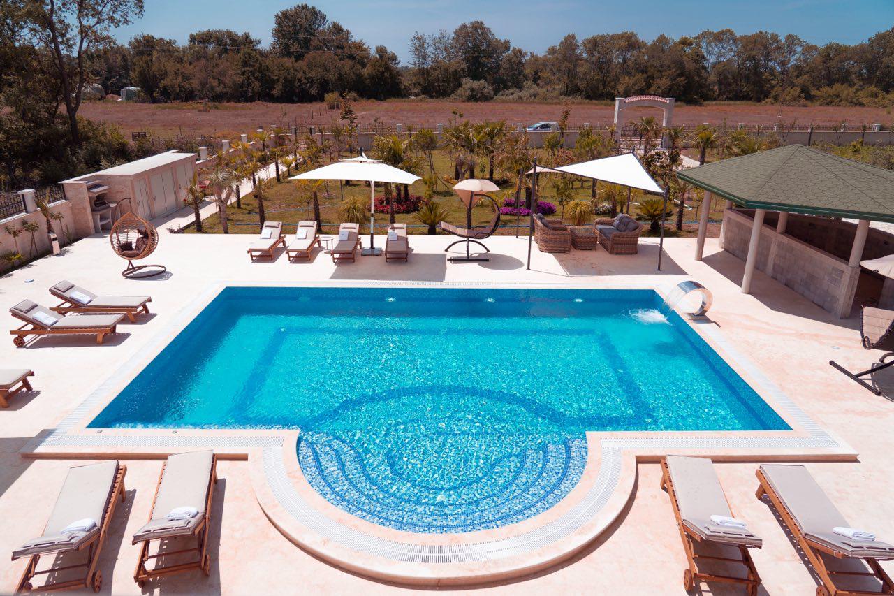 Luxurious pool with curved steps, lounge area, and scenic greenery&mdash;ideal Ulcinj property investment via montenegro-listings.me by ekosphere doo.