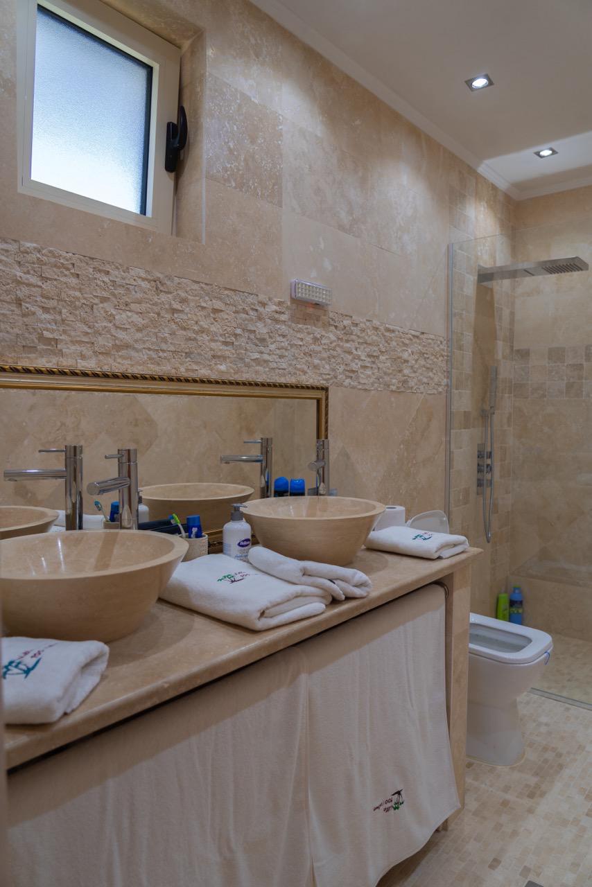 Elegant modern bathroom in Ulcinj real estate, tiled, dual vessel sinks, glass shower; exclusive on montenegro-listings.me by ekosphere doo.