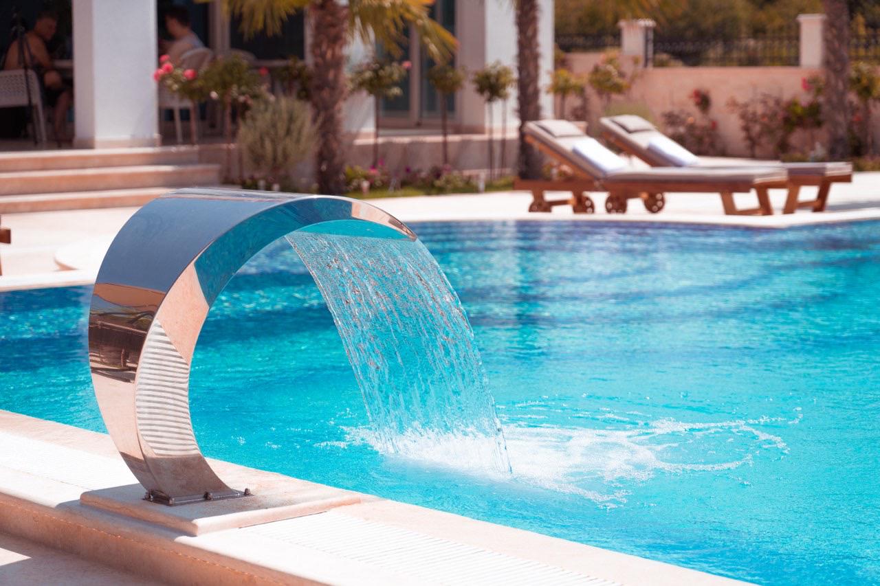 Luxury Ulcinj villa: sleek pool, waterfall feature, palm trees, stylish lounges&mdash;exclusive Montenegro real estate by Ekosphere | montenegro-listings.me.