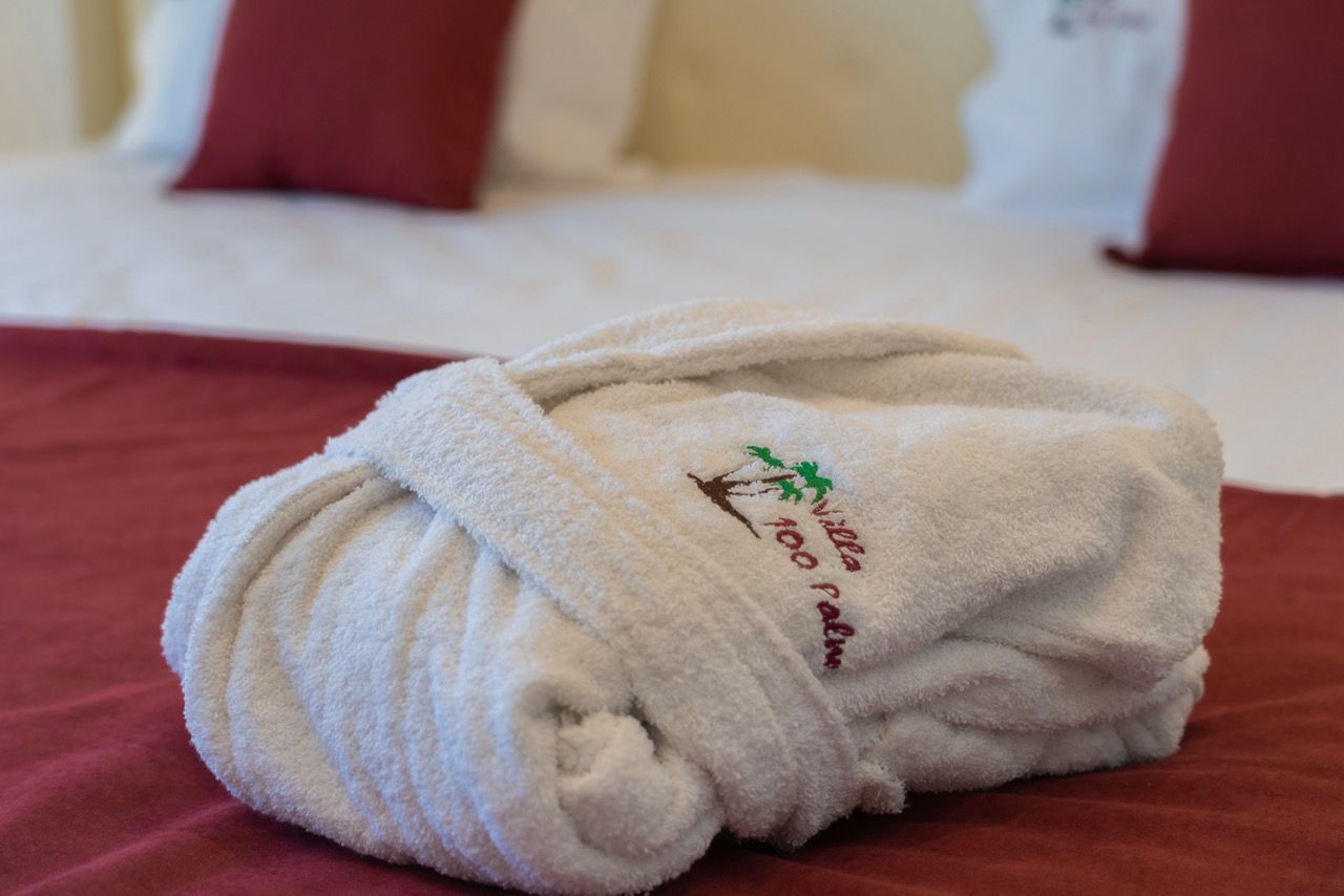 Luxurious folded white bathrobe on burgundy bedding in Ulcinj&mdash;exclusive comfort at Ekosphere DOO, via montenegro-listings.me.