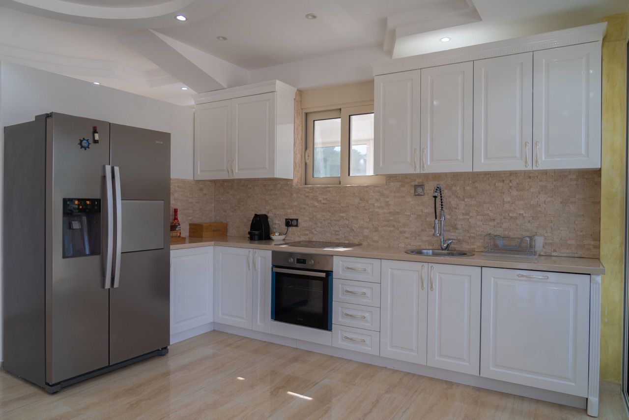 Stunning Ulcinj kitchen: sleek white cabinets, tiled backsplash, stainless appliances. Invest in Montenegro real estate with Ekosphere.