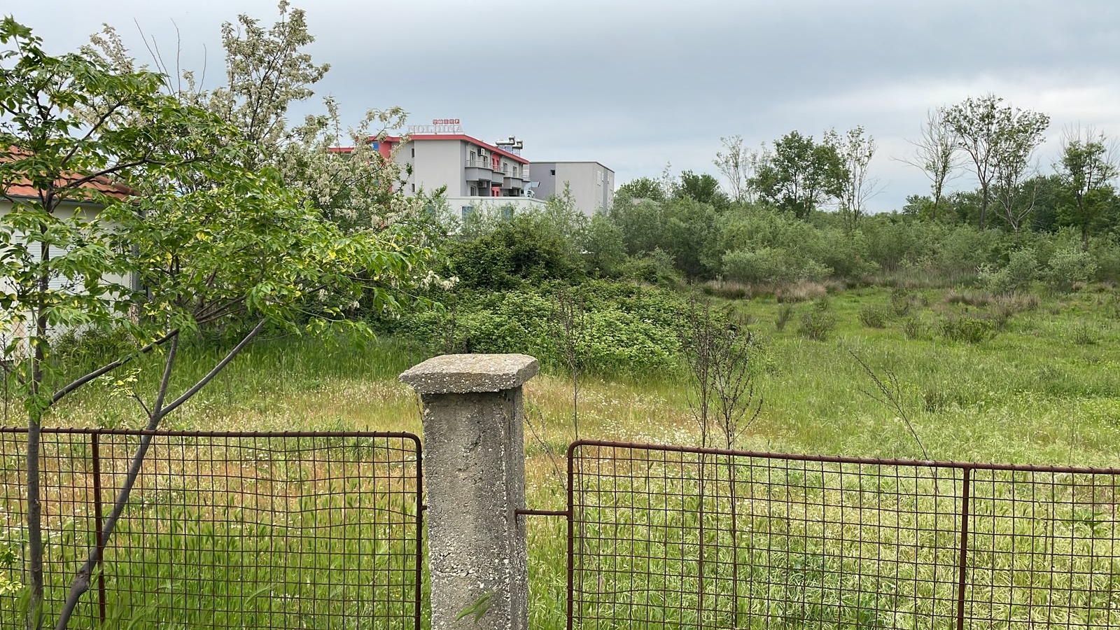 Prime Ulcinj, Montenegro property: lush field, scenic views, modern home with red roof&mdash;exclusive at montenegro-listings.me by Ekosphere doo.