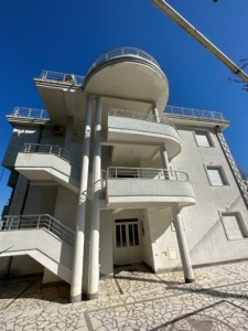 Stunning modern 3-story property in Ulcinj, Montenegro—rounded balconies, tiled walkway. Invest via montenegro-listings.me by ekosphere doo.