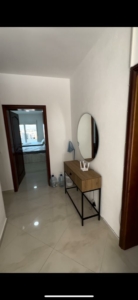 Elegant hallway in Ulcinj real estate with glossy tiles, stylish console, mirror, open to a cozy bedroom—montenegro-listings.me by ekosphere doo.
