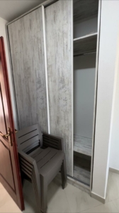 Modern wood-finish wardrobe, light tiled floors, and stacked chairs enhance this Ulcinj property—exclusive with montenegro-listings.me by ekosphere doo.