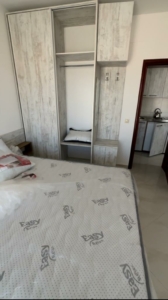 Modern Ulcinj bedroom with cozy bed, wardrobe, kitchen access—prime Montenegro real estate by ekosphere doo at montenegro-listings.me.