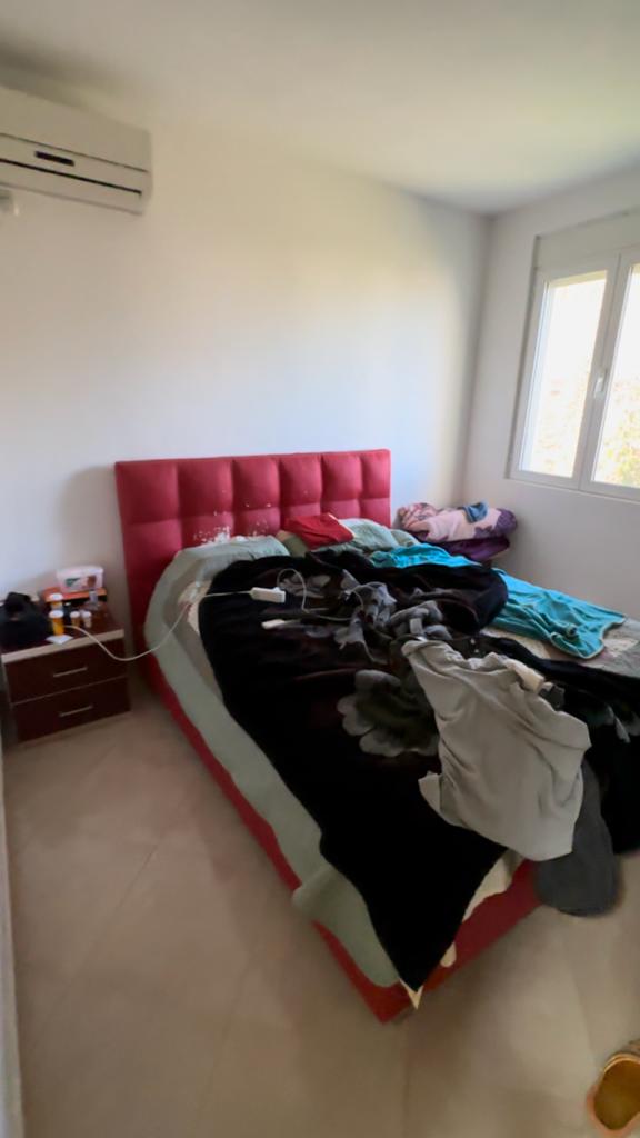 Modern Ulcinj bedroom with red tufted headboard, natural light, AC unit; top Montenegro property at montenegro-listings.me by Ekosphere.