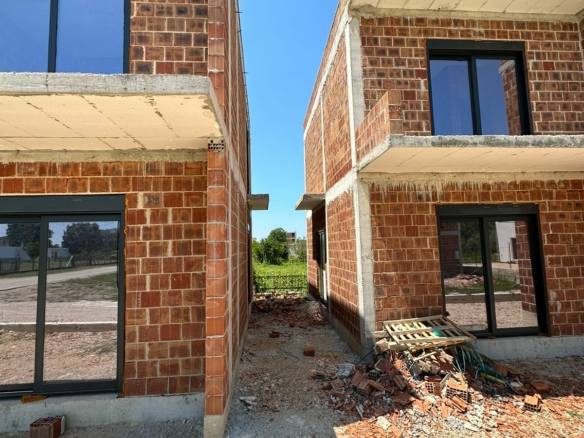 Prime Ulcinj investment: two unfinished brick homes with glass features, ideal for custom development. Listed by Ekosphere on montenegro-listings.me.