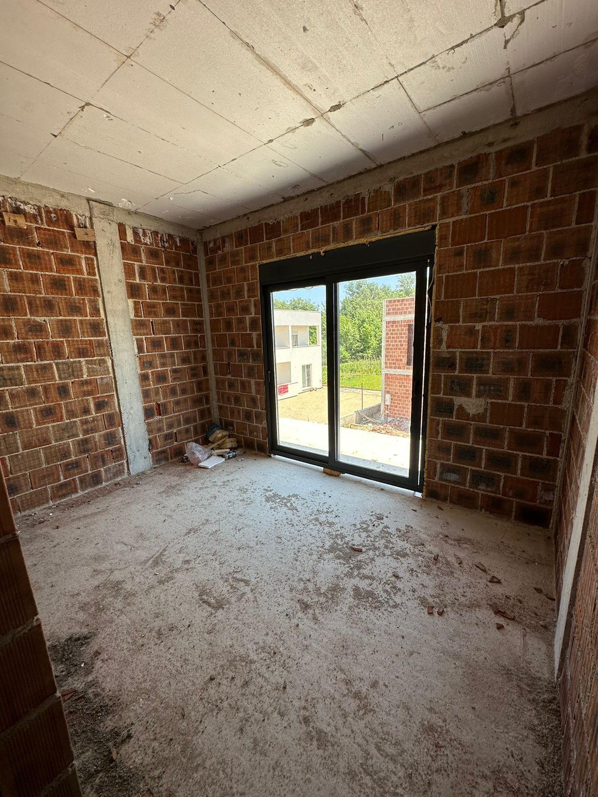 Unfinished room with brick walls, concrete ceiling, and wide glass doors overlooking Ulcinj&rsquo;s property market&mdash;exclusive by Ekosphere, montenegro-listings.me.