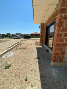 Modern brick building by Ekosphere with glass doors, gravel yard, and Ulcinj real estate views—exclusive at montenegro-listings.me.