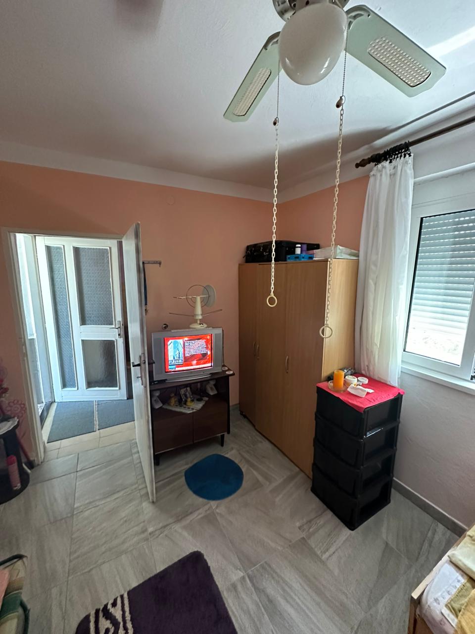 Modern Ulcinj room with tiled floors, ceiling fan, wardrobe, and TV. Prime real estate by Ekosphere DOO on montenegro-listings.me.