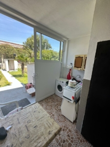 Modern Ulcinj laundry area with washer, stove, tiled floors, glass garden door—ideal eco-investment at montenegro-listings.me by Ekosphere.