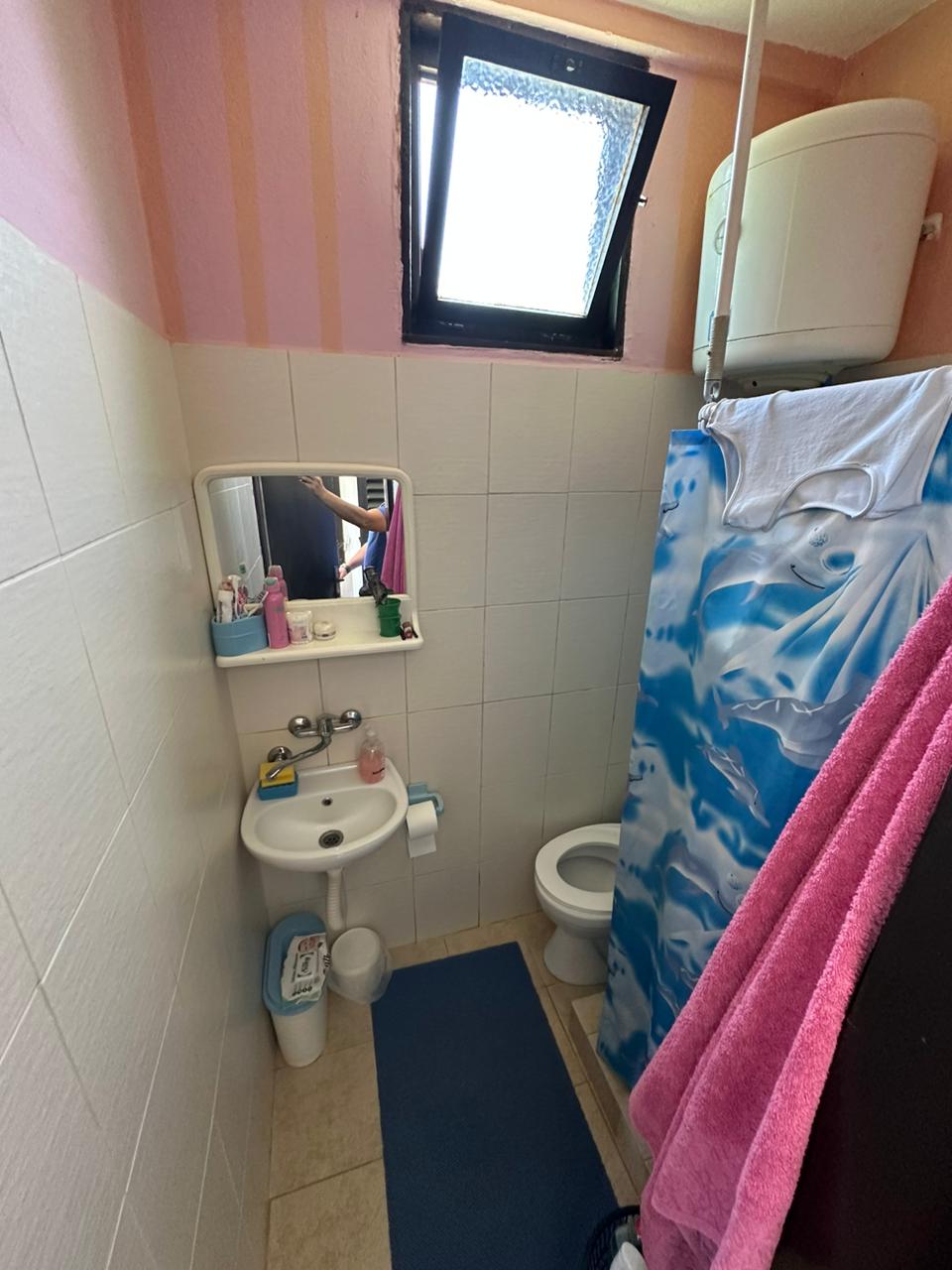 Bright bathroom in Ulcinj property: white tiles, sink with mirror, shower, window. Invest via montenegro-listings.me by Ekosphere doo.