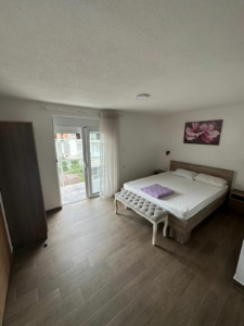 Luxury Ulcinj bedroom with double bed, bench, wardrobe, and bright window. Invest in Montenegro real estate—Ecosphere quality by montenegro-listings.me.