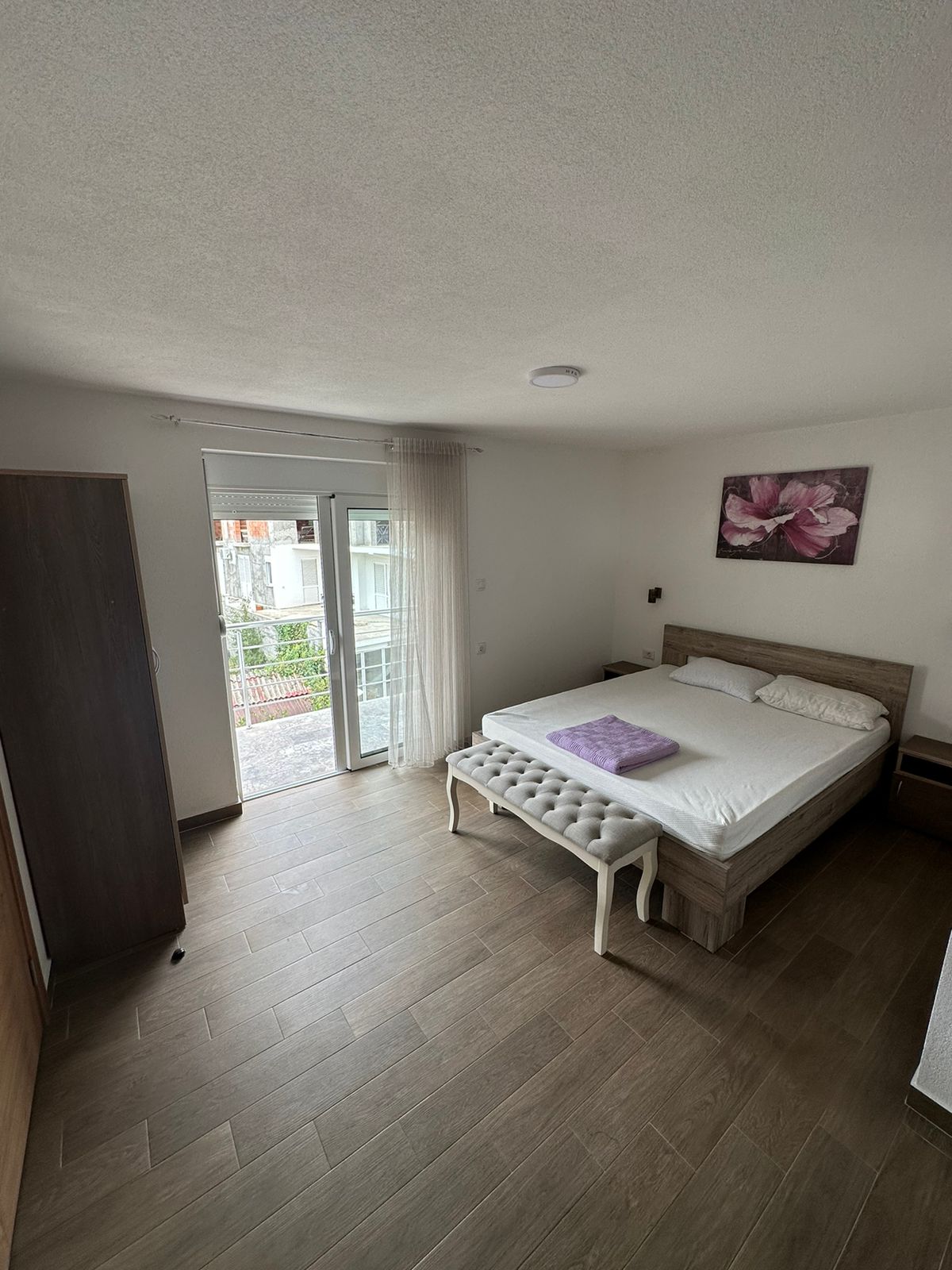 Luxury Ulcinj bedroom with double bed, bench, wardrobe, and bright window. Invest in Montenegro real estate&mdash;Ecosphere quality by montenegro-listings.me.