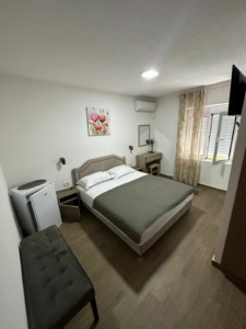 Modern hotel room in Ulcinj: double bed, desk, AC, TV—perfect Montenegro property investment via montenegro-listings.me by ekosphere doo.