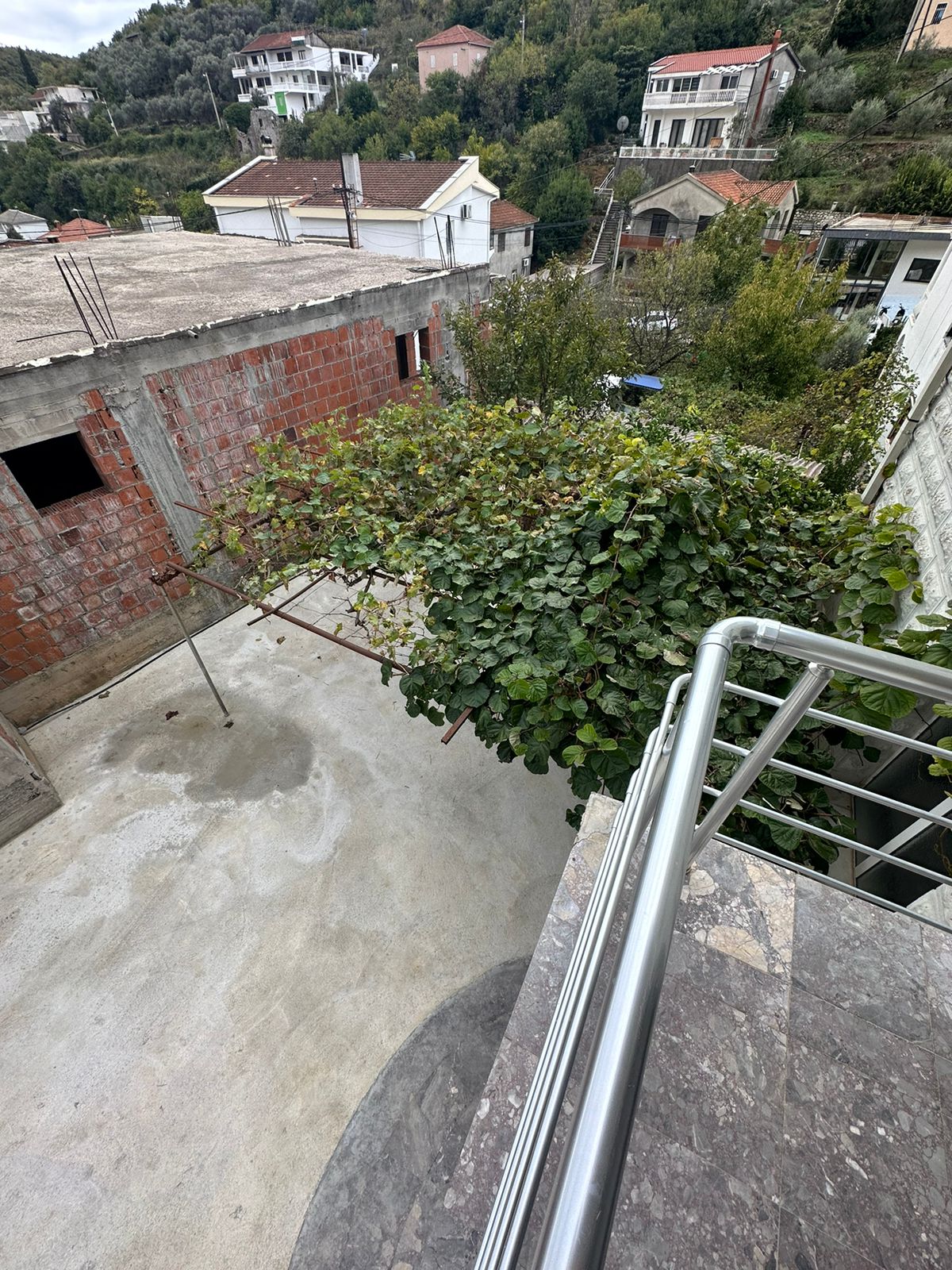 Stunning Ulcinj property view: balcony overlooks vine trellis, concrete yard, ekosphere homes in scenic hills. Invest at montenegro-listings.me.